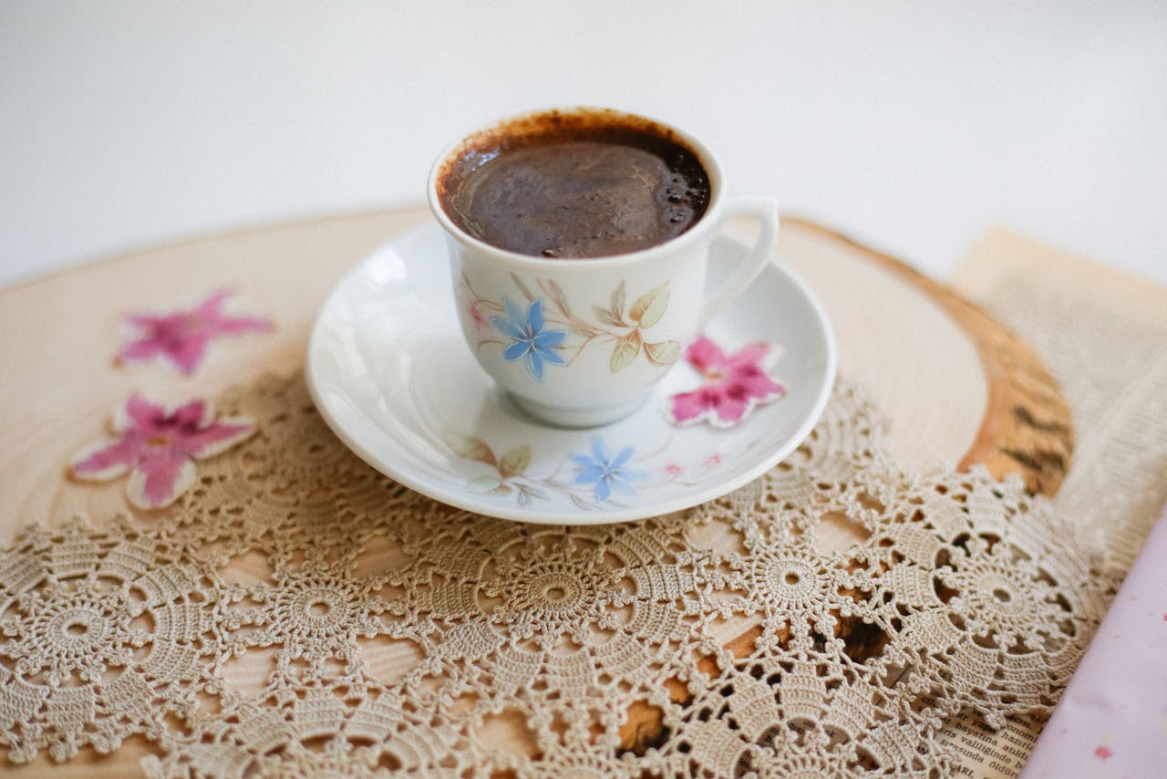 who-we-are Delicate coffee cup with rich coffee on vintage lace and wooden placemat.